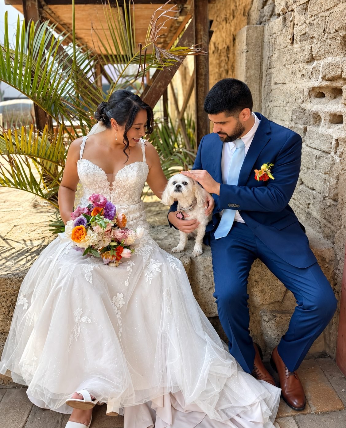 Novios con su perrito y un ramo colorido en un patio de cantera