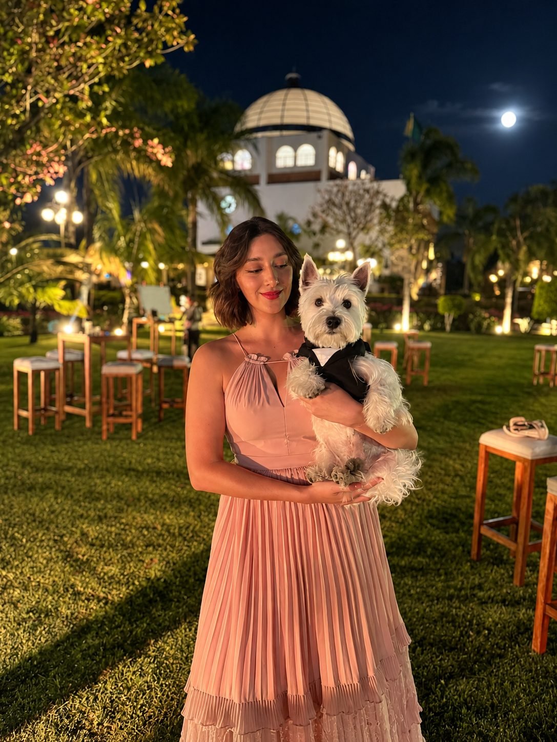 Asistente de The Woofdding Assistant sosteniendo con cariño a un perrito con esmoquin en una boda